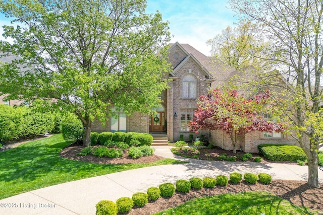 traditional-style house featuring a front yard and brick siding