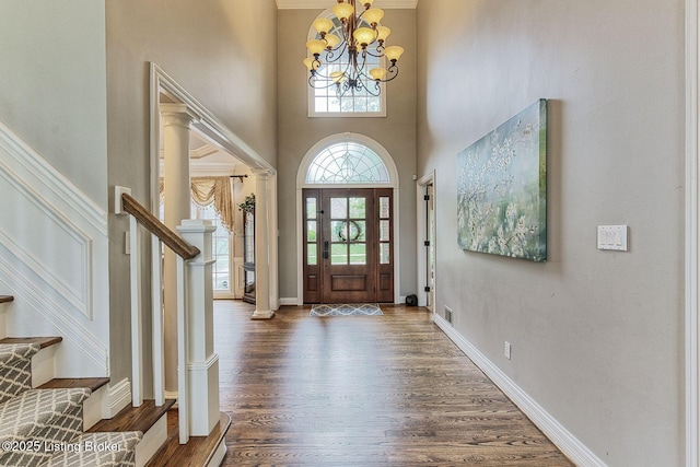 foyer entrance featuring stairs, baseboards, wood finished floors, a notable chandelier, and a high ceiling