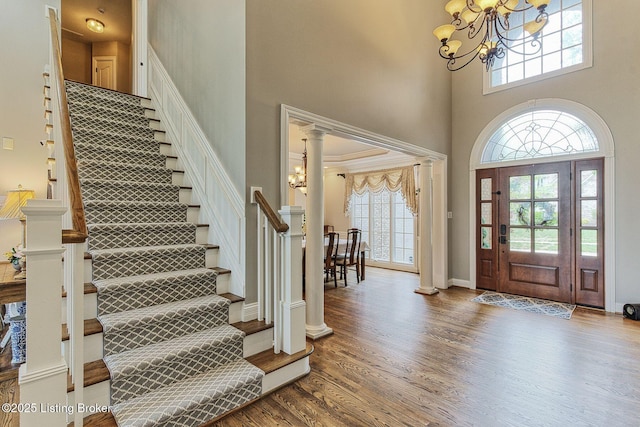 entryway with stairway, a wealth of natural light, a notable chandelier, and a high ceiling