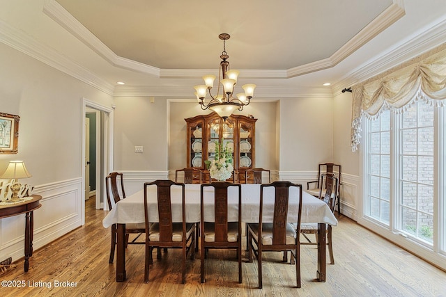 dining room featuring a chandelier, light wood-type flooring, crown molding, and a tray ceiling