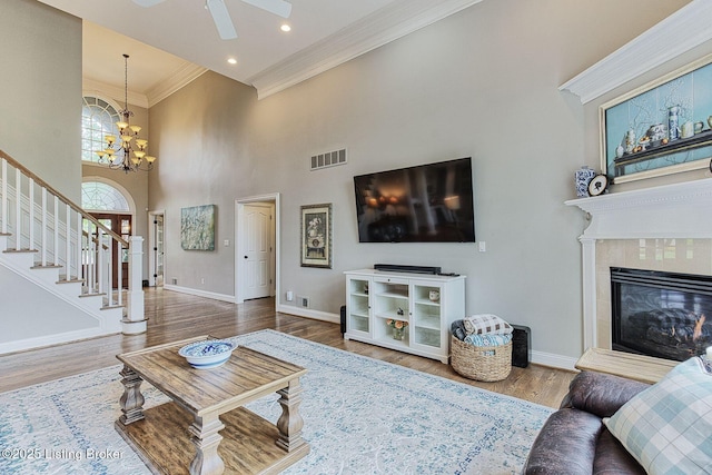 living area featuring wood finished floors, stairs, ornamental molding, baseboards, and visible vents