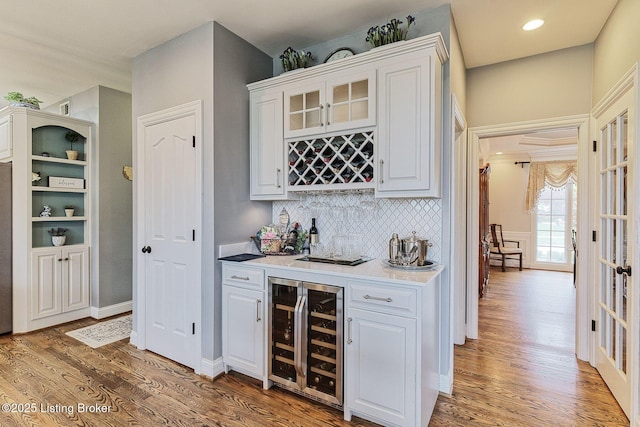 bar with a bar, wine cooler, tasteful backsplash, baseboards, and wood finished floors