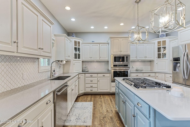 kitchen with a chandelier, stainless steel appliances, white cabinets, and a sink