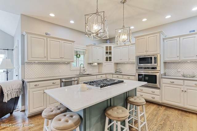 kitchen featuring a sink, a chandelier, a kitchen bar, light wood-type flooring, and appliances with stainless steel finishes