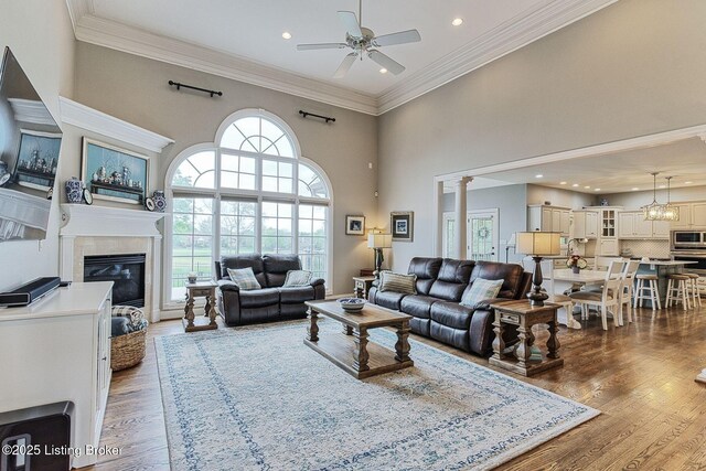 living room featuring a wealth of natural light, a glass covered fireplace, wood finished floors, and a ceiling fan
