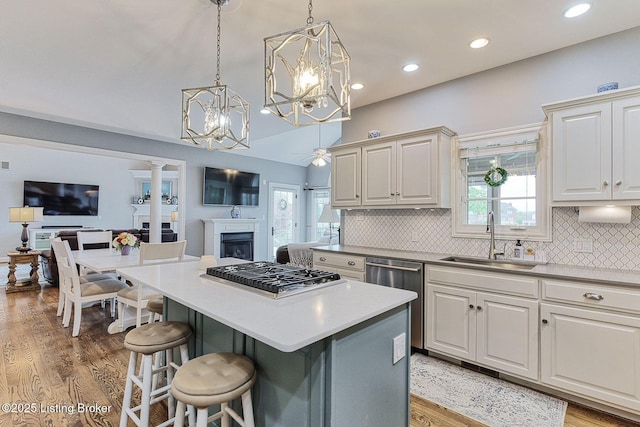 kitchen featuring a sink, decorative backsplash, a center island, appliances with stainless steel finishes, and open floor plan