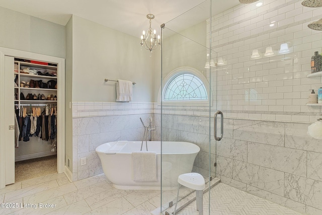 bathroom featuring a chandelier, a stall shower, tile walls, a freestanding tub, and a spacious closet