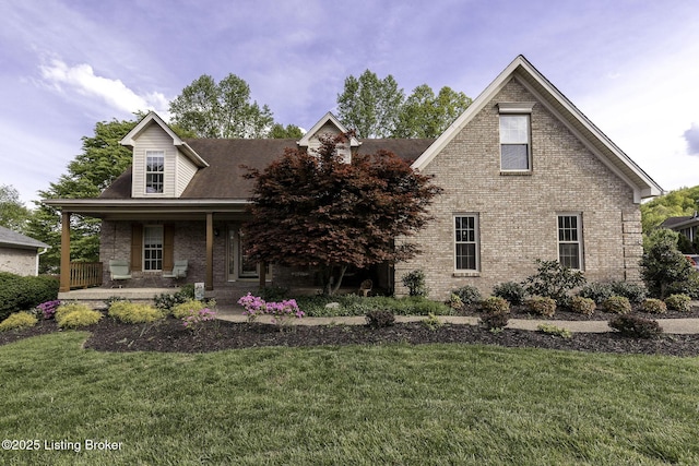 view of front of home with a porch, a front lawn, and brick siding