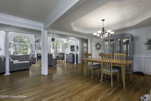 dining space with a chandelier, wood finished floors, stairs, a fireplace, and ornamental molding