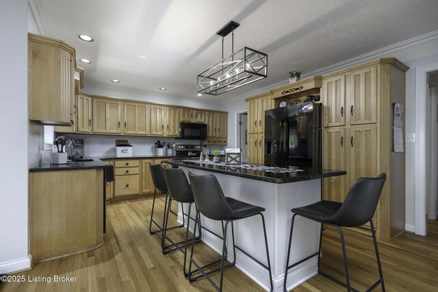 kitchen with light wood-style flooring, a notable chandelier, black appliances, crown molding, and a breakfast bar area