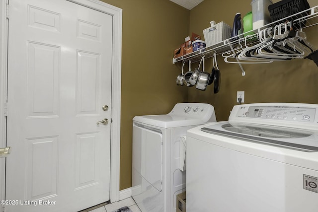 clothes washing area featuring washing machine and clothes dryer, light tile patterned flooring, and laundry area