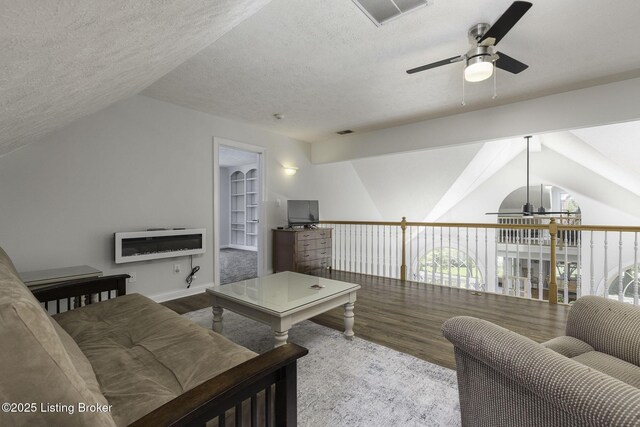 living room with a textured ceiling, vaulted ceiling, visible vents, a ceiling fan, and wood finished floors