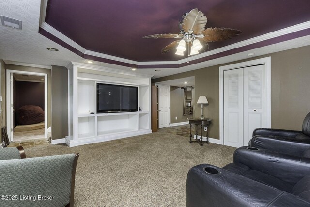 living room with ceiling fan, crown molding, carpet flooring, and a tray ceiling