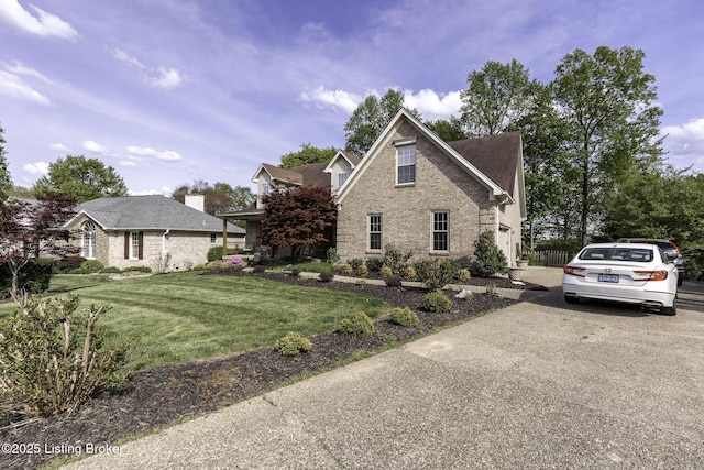 view of home's exterior featuring brick siding, a lawn, and concrete driveway
