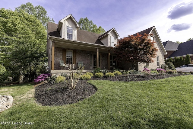 cape cod home featuring brick siding, a porch, and a front yard