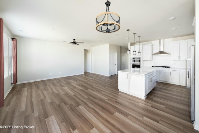 3611 Fordham Pk Dr, Louisville, KY 40245 - kitchen with wall chimney range hood, a ceiling fan, open floor plan, a kitchen island, and white cabinets