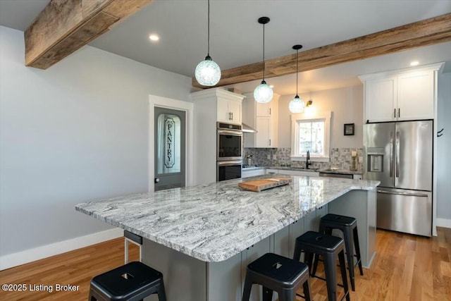 306 E Washington St, La Grange, KY 40031 - kitchen featuring a breakfast bar area, white cabinetry, beamed ceiling, backsplash, and appliances with stainless steel finishes