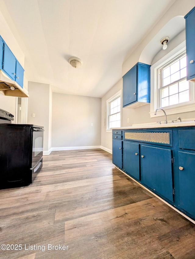 1104 Oleanda Ave, Louisville, KY 40215 - kitchen featuring blue cabinetry, wood finished floors, baseboards, black / electric stove, and light countertops