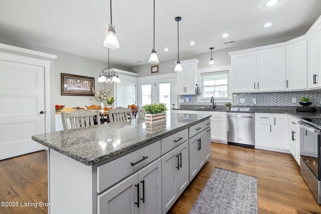 kitchen with tasteful backsplash, dark stone countertops, stainless steel appliances, visible vents, and a kitchen island