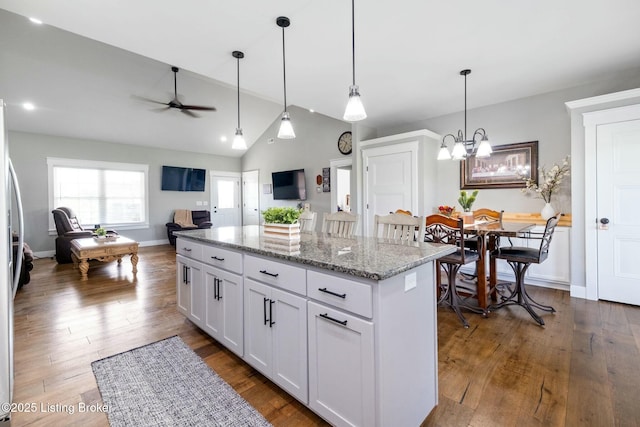 kitchen with vaulted ceiling, ceiling fan with notable chandelier, open floor plan, white cabinets, and dark wood-type flooring