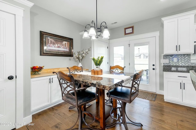 dining area with visible vents, dark wood-style flooring, and an inviting chandelier