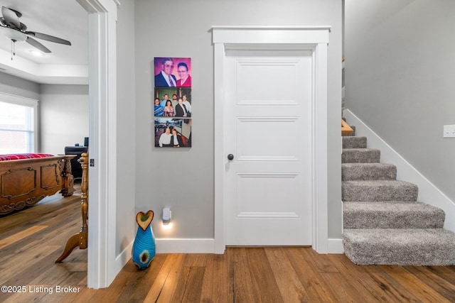 stairway with baseboards, a ceiling fan, and wood finished floors