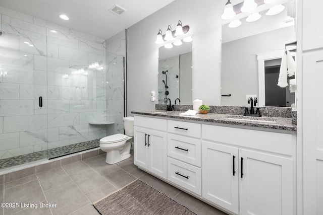bathroom featuring a shower stall, double vanity, visible vents, toilet, and a sink
