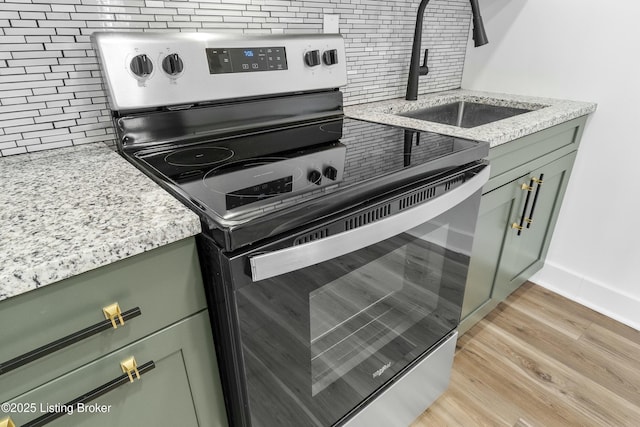 kitchen featuring backsplash, green cabinetry, stainless steel electric range oven, and a sink