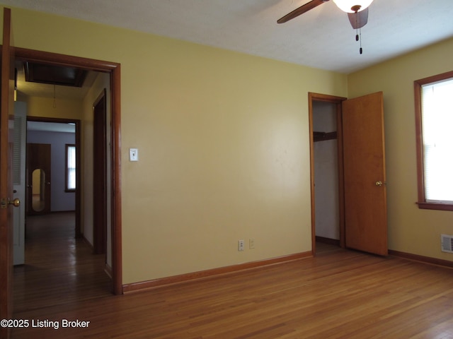 unfurnished bedroom with baseboards, visible vents, wood finished floors, and attic access