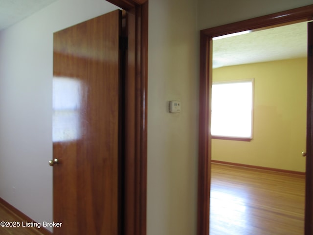 hallway with wood finished floors and baseboards