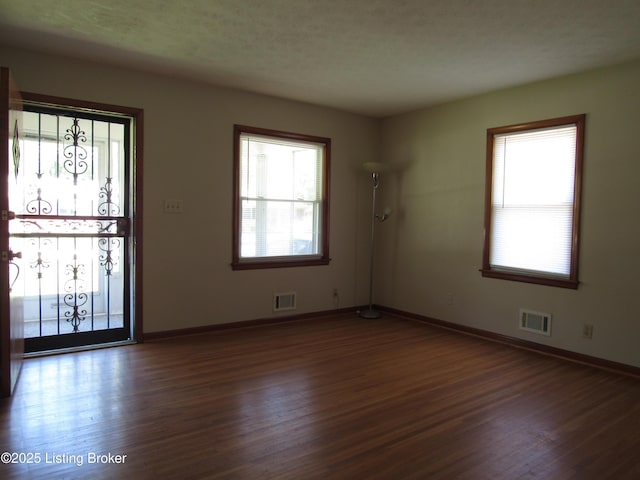 empty room featuring baseboards, visible vents, and wood finished floors