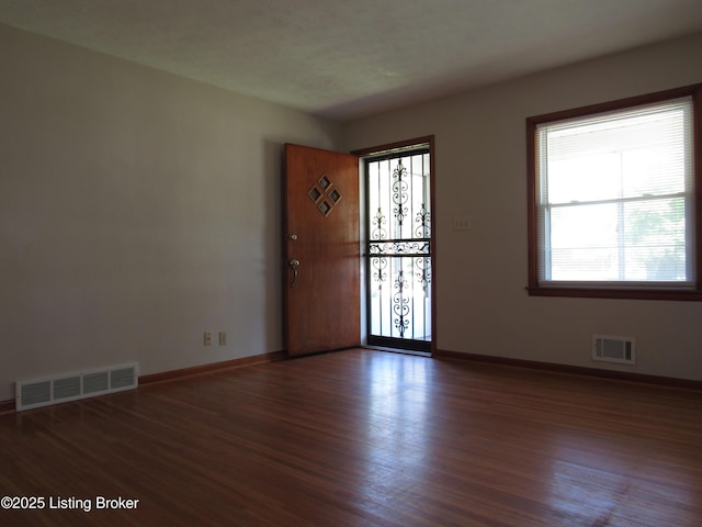 unfurnished room featuring baseboards, visible vents, and wood finished floors