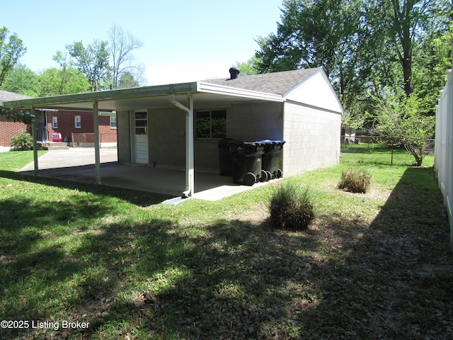 exterior space featuring a yard, concrete block siding, fence, a shingled roof, and a patio area