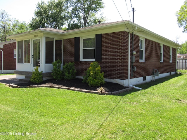view of side of home with brick siding, a yard, and a sunroom