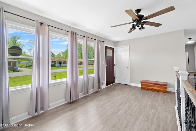 unfurnished living room with baseboards, a ceiling fan, and wood finished floors