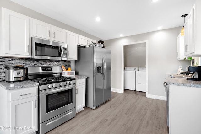 kitchen with washing machine and dryer, decorative backsplash, white cabinets, and stainless steel appliances