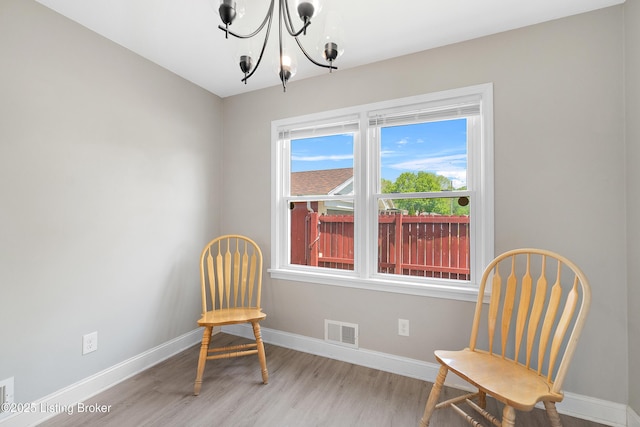 living area with a chandelier, light wood-style flooring, visible vents, and baseboards