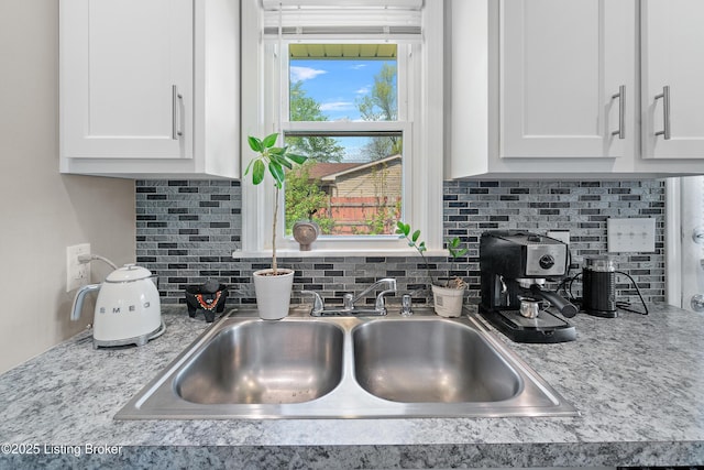 details with white cabinets, backsplash, and a sink