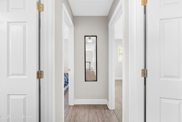 hallway with baseboards, carpet flooring, and wood finished floors