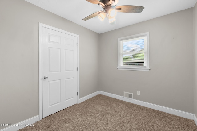 carpeted empty room featuring baseboards, visible vents, and ceiling fan