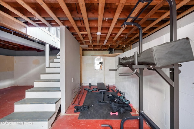 basement featuring concrete block wall and stairway