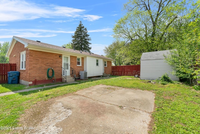 back of house featuring fence, entry steps, a yard, and central air condition unit
