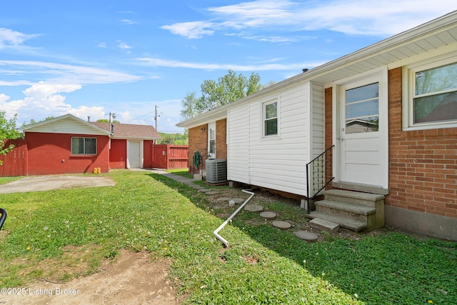 rear view of property with a gate, cooling unit, fence, entry steps, and a yard