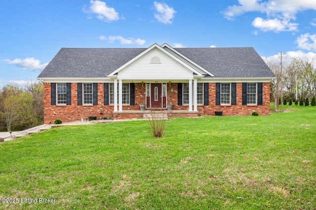 single story home featuring a porch, a shingled roof, brick siding, and a front yard