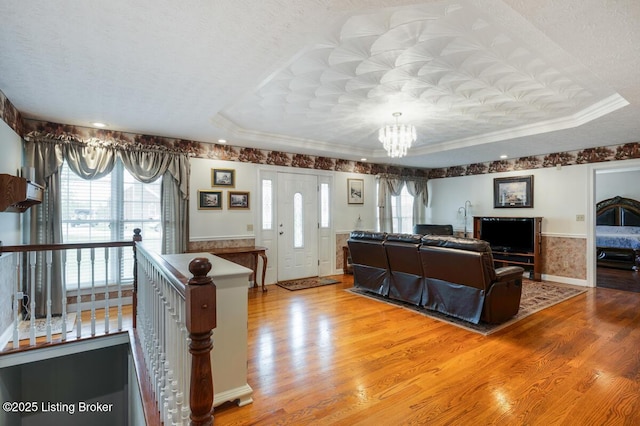 living room featuring a raised ceiling, wood finished floors, and an inviting chandelier