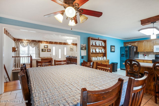 dining room with ceiling fan with notable chandelier, baseboards, ornamental molding, and light tile patterned flooring