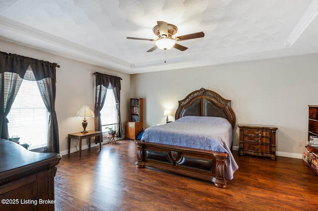 bedroom featuring baseboards, wood finished floors, and a raised ceiling