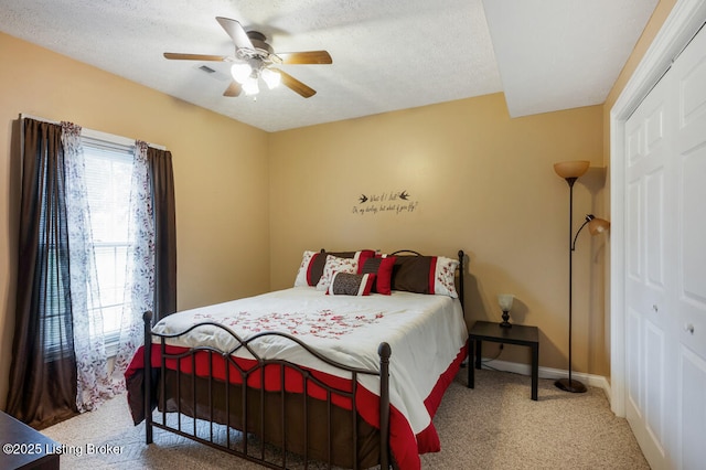 bedroom featuring a ceiling fan, a textured ceiling, baseboards, carpet flooring, and visible vents