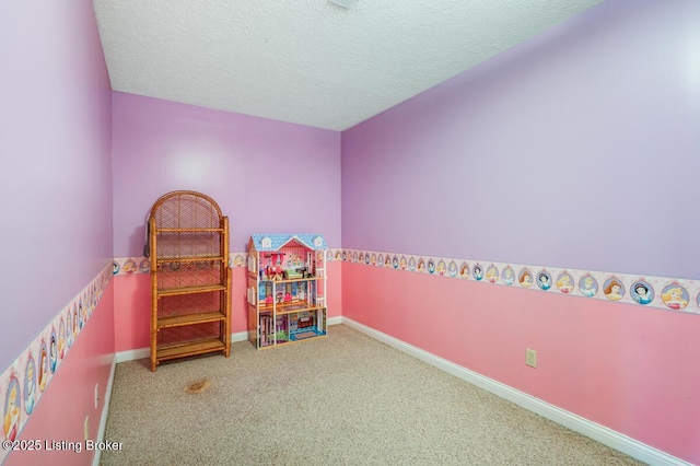recreation room with carpet floors, a textured ceiling, and baseboards