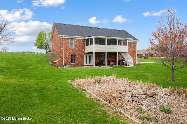 back of property featuring brick siding, a sunroom, and a lawn